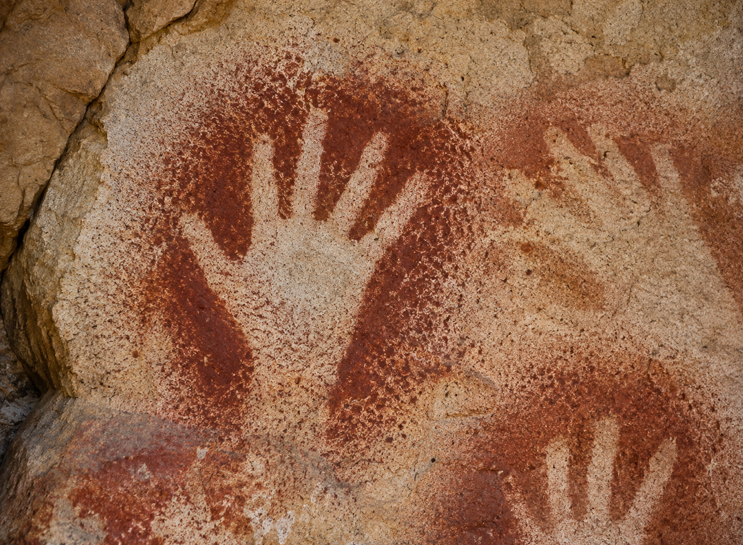Ancient ochre hand stencil preserved on a cave wall.