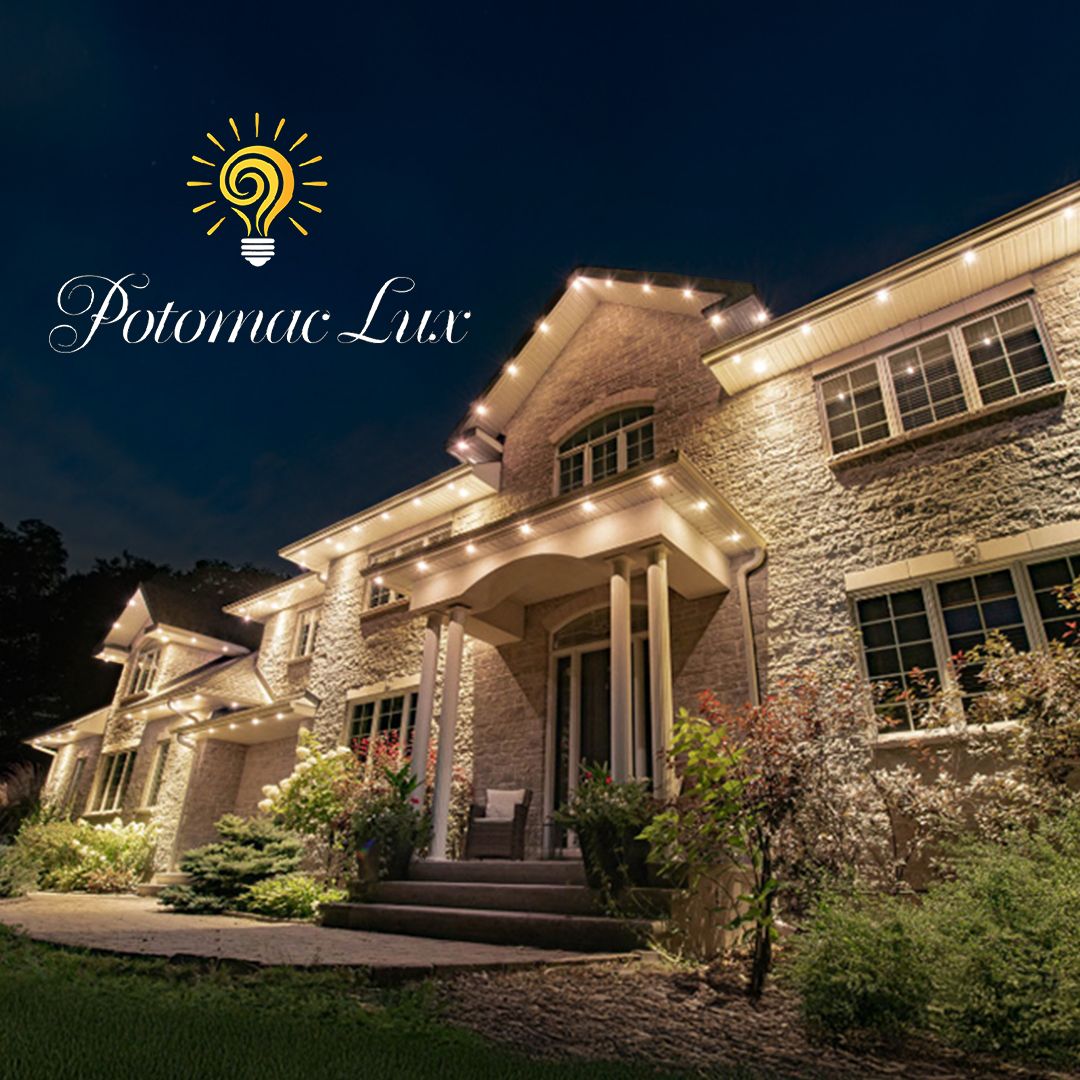 A stone home's roofline, façade, and entrance illuminated at night, from the Potomac Lux lighting archive.